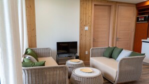 A cozy living room with wicker furniture, a flat-screen TV, and wooden doors.