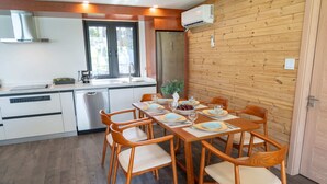 Eine moderne Küche mit weißen Schränken, einem Edelstahlkühlschrank und einem Holzespeisesaal, gedeckt für sechs Personen mit Holzstühlen.