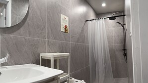 Een moderne badkamer met toilet, wastafel en douche.