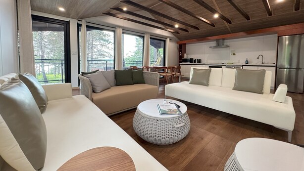 Een moderne woonkamer met twee banken, een ronde salontafel en een keuken op de achtergrond.