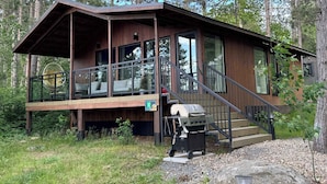 Een chalet met een overdekte veranda, een barbecue en een rolstoeltoegankelijke hellingbaan.