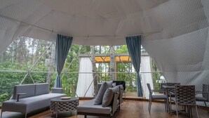 A spacious tent with a geometric ceiling, a sofa, a small table, and a chair.