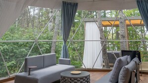 A modern, spacious interior with a large, circular skylight and a view of a forested area.