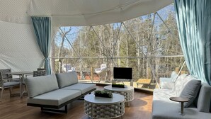 A spacious tent with a modern interior, featuring a sofa, a coffee table, and a TV.