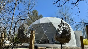 A geodesic dome structure with a hanging chair and a wooden deck. - Algonquin's Edge Resort | Dome 7 (South Algonquin)