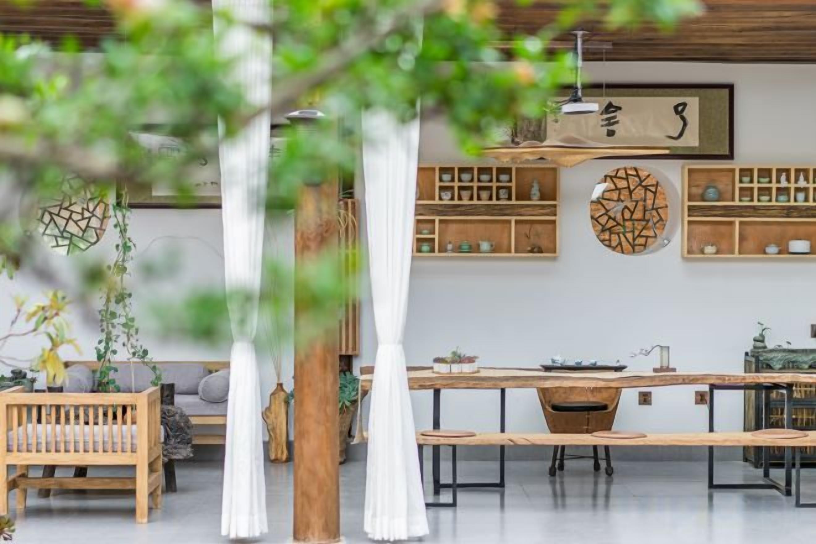 Um interior moderno com um banco de madeira, uma mesa de jantar e uma planta pendente.