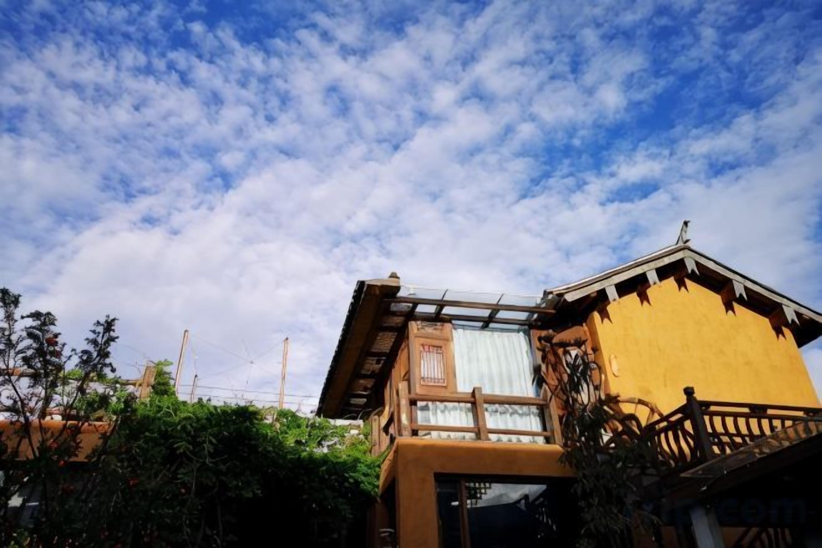 A building with a balcony and a window overlooking a garden.