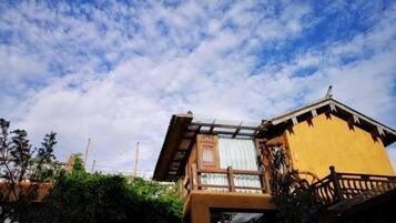 A building with a balcony and a window overlooking a garden.