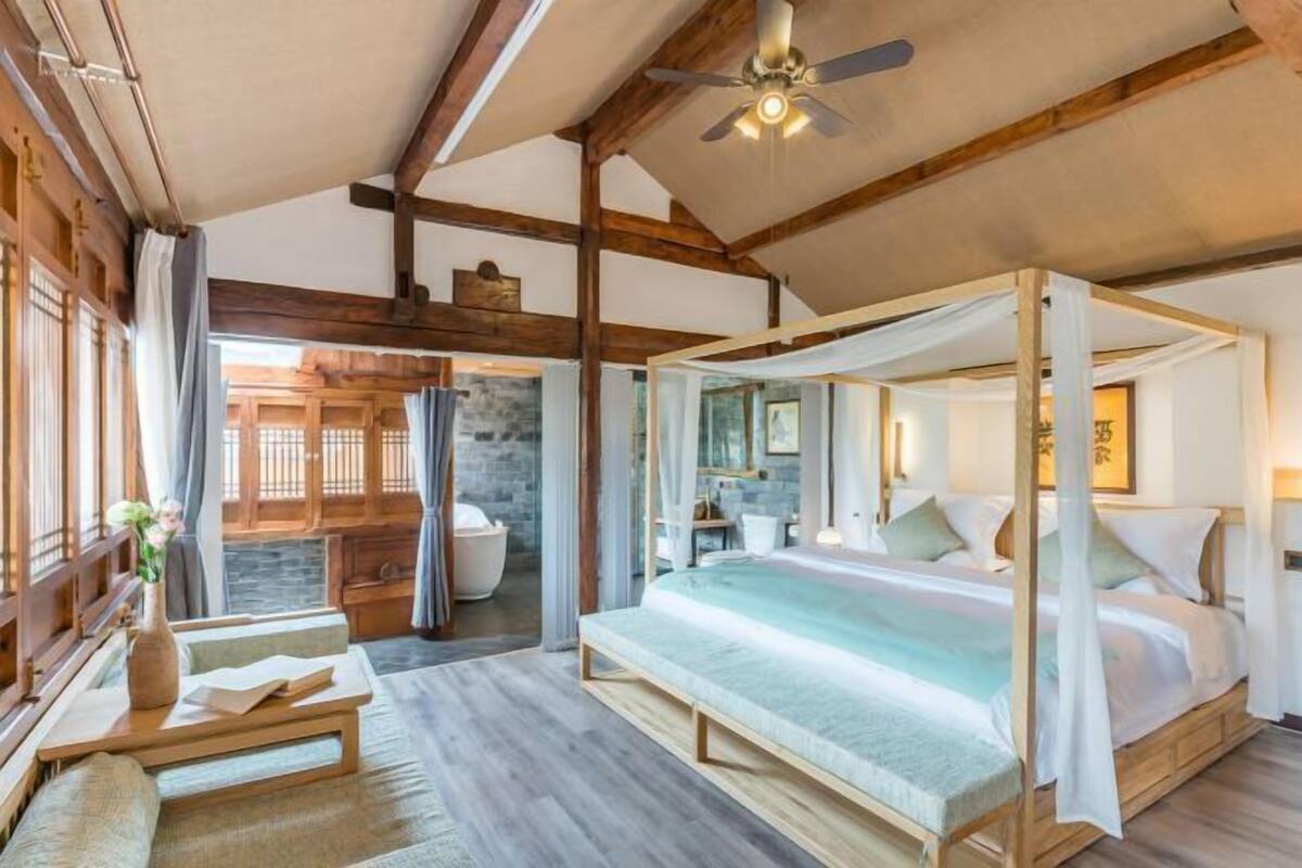 A traditional Japanese-style bedroom with a four-poster bed, wooden beams, and a ceiling fan.