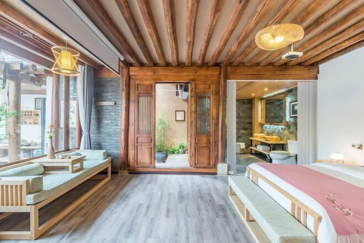 A modern room with a wooden ceiling, a bed, a bench, and a small table.