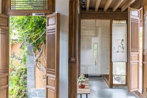 Un intérieur japonais traditionnel avec des portes coulissantes, un sol recouvert de tatamis et une vue sur un jardin.