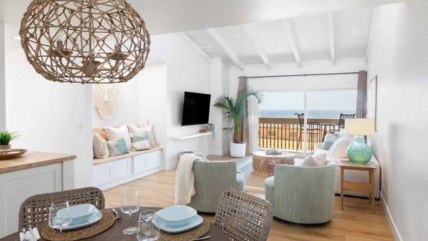 Ein modernes Wohnzimmer mit Essbereich, einer großen gewebten Leuchte und Blick auf das Meer.