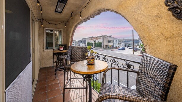 Ein Balkon mit Korbmöbeln, einem Tisch und einem Blumentopf.