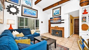 Ein Wohnzimmer mit einem blauen Sofa, einem Kamin und verschiedenen gerahmten Bildern an den Wänden.