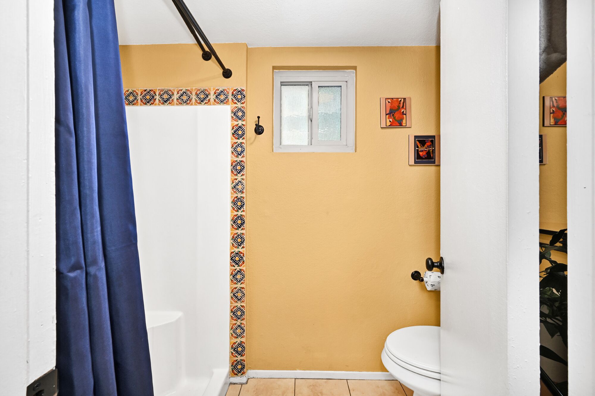 Ein kleines Badezimmer mit Duschvorhang, Fenster und Toilette.