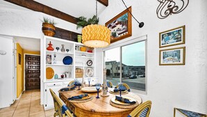 Un coin repas avec une table et des chaises en bois, entouré d’étagères où sont exposés divers objets décoratifs.
