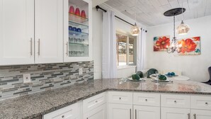 A modern kitchen with white cabinets, a granite countertop, and a glass display shelf. - Lovely 2BA King Beds+2 Car Garage. Hidden Gem-Walk>Shops & Dining! (Littleton)