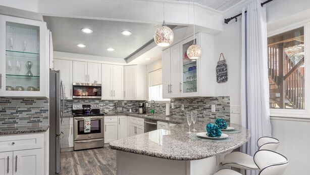 A modern kitchen with white cabinetry, granite countertops, and a central island with bar stools. - Lovely 2BA King Beds+2 Car Garage. Hidden Gem-Walk>Shops & Dining! (Littleton)