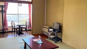 A room with tatami mats, a wooden table, chairs, a heater, a TV, and a window with a view. - ishiuchiskicenter (Minamiuonuma)