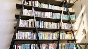 A bookshelf filled with books, a ladder, and a white wall. - ishiuchiskicenter (Minamiuonuma)