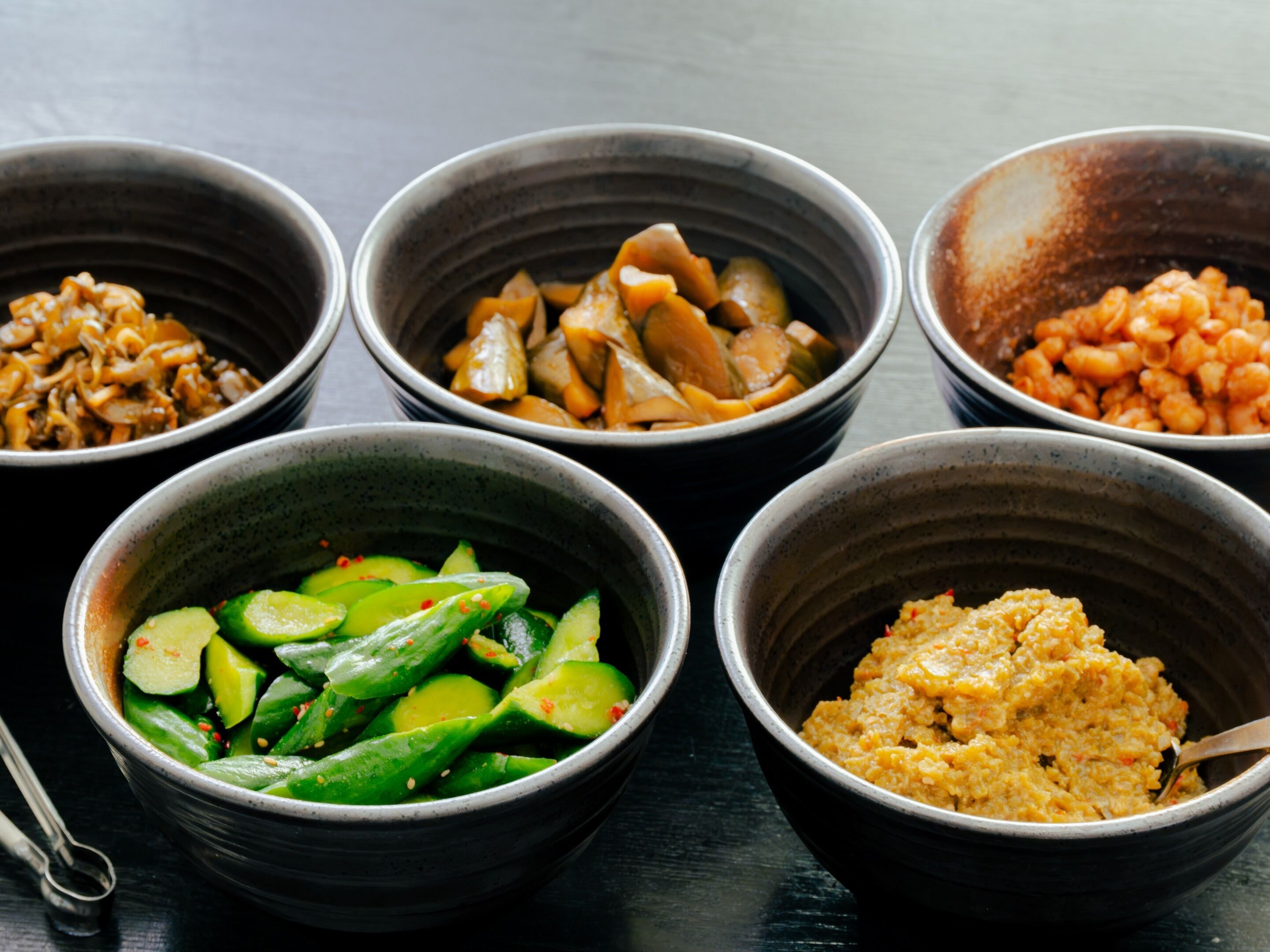 A table with five bowls containing different food items.