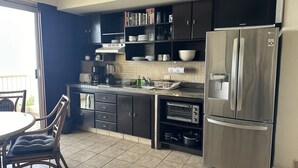 Una cucina moderna con mobili scuri, elettrodomestici in acciaio inossidabile e un'area pranzo con sedie in vimini.