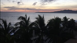 Una vista sulla costa con palme e un tramonto.