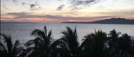 Une vue sur la côte, avec des palmiers et un coucher de soleil.