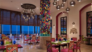 Una sala ristorante con diversi tavoli e sedie, ampie finestre e lampade sferiche a sospensione.