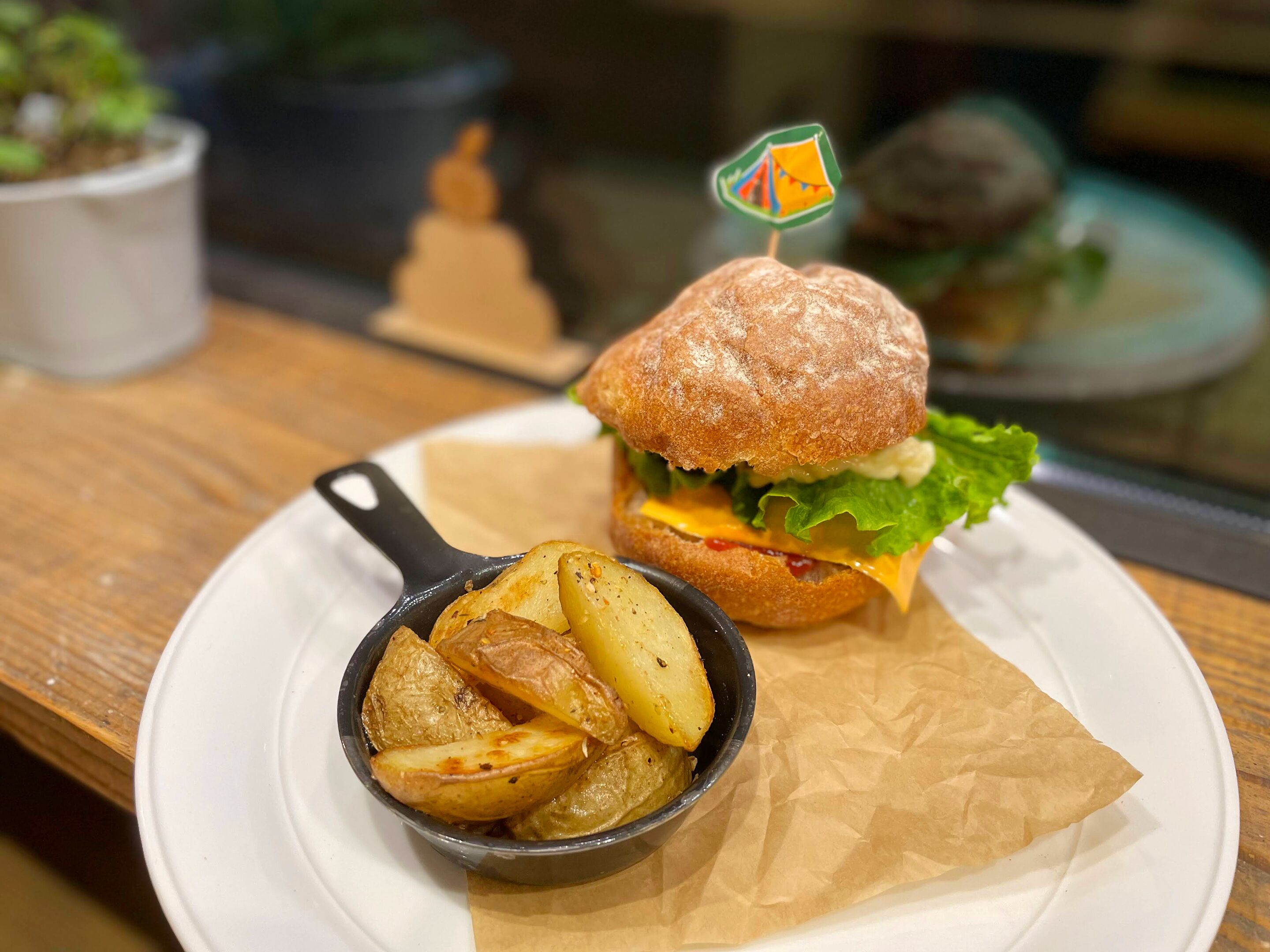 A meal consisting of a burger, fries, and a small pot of sauce on a white plate.