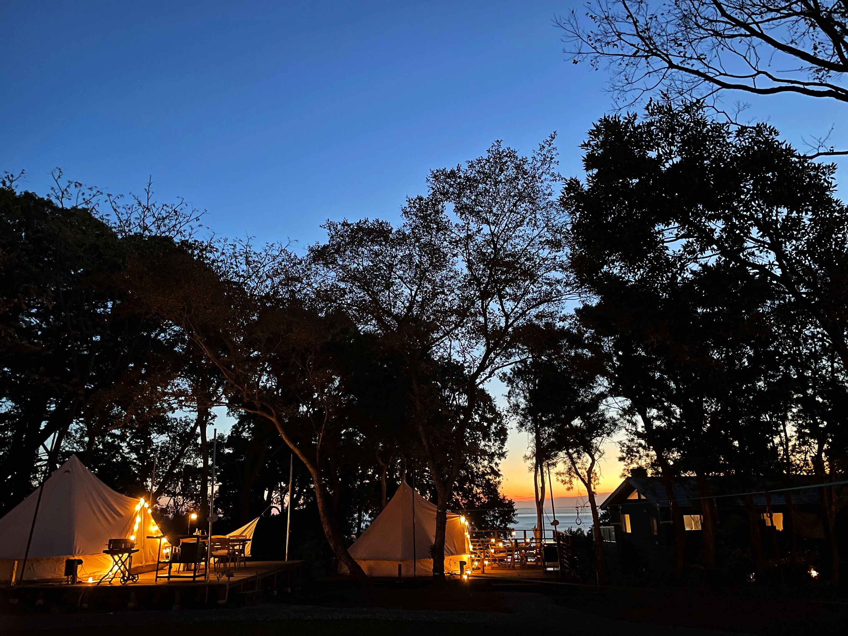 Ein Campingplatz mit Zelten und einer Terrassenfläche im Abenddämmerung.