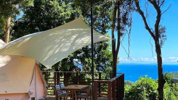 A tent with a table and chairs on a wooden deck, overlooking a scenic view of the ocean. - COUSCOUS Glamping Manazuru (Manazuru)