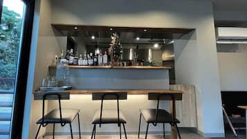 A modern kitchen with a bar area, featuring a wooden countertop, three black chairs, and a Christmas tree decoration.