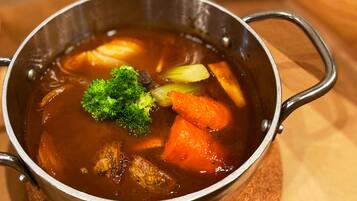 Een metalen pot met handgrepen, gevuld met een stoofpot met groenten en vlees.
