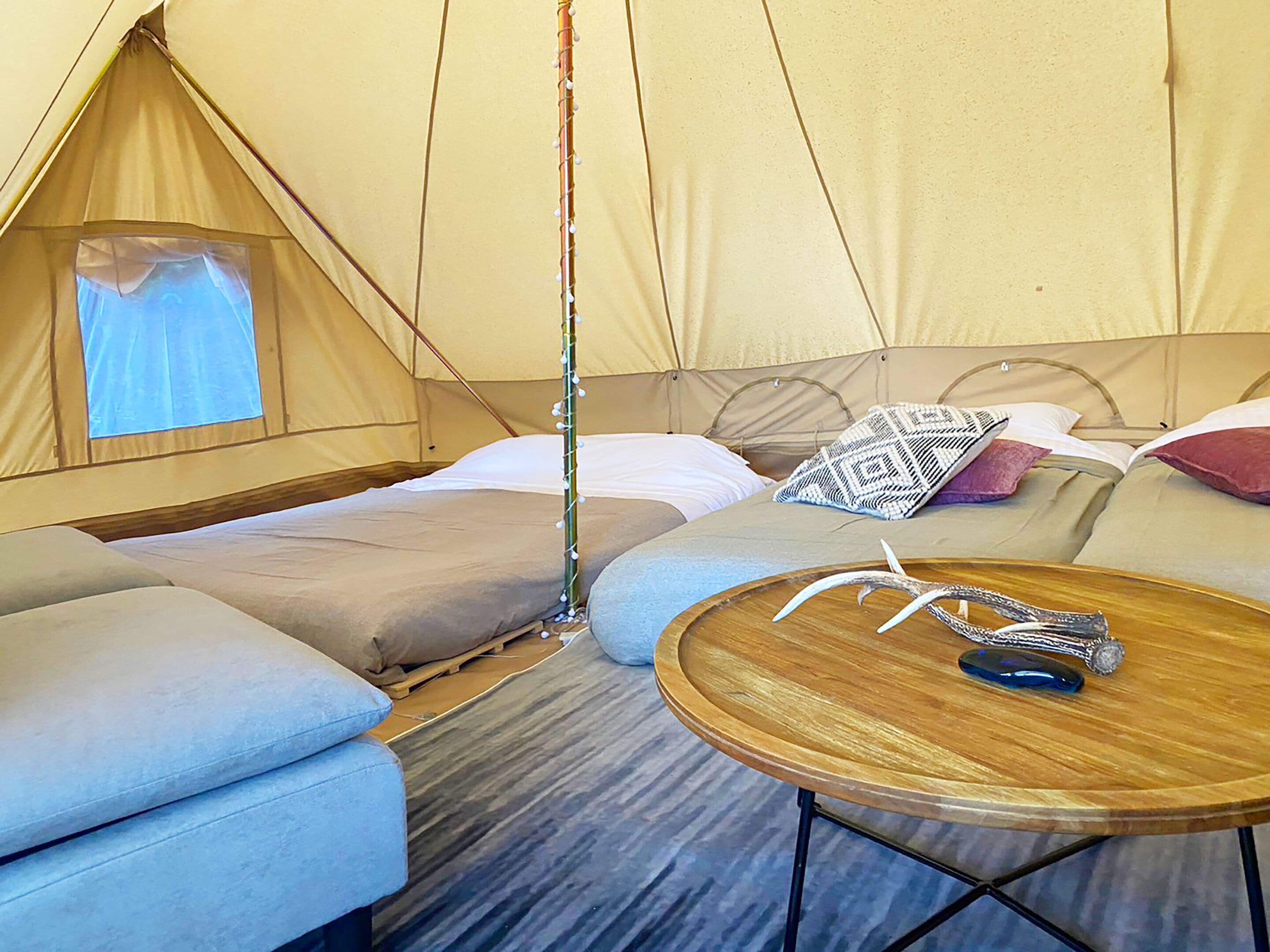 Een gezellige tent met een bed, een tafeltje en een raam.