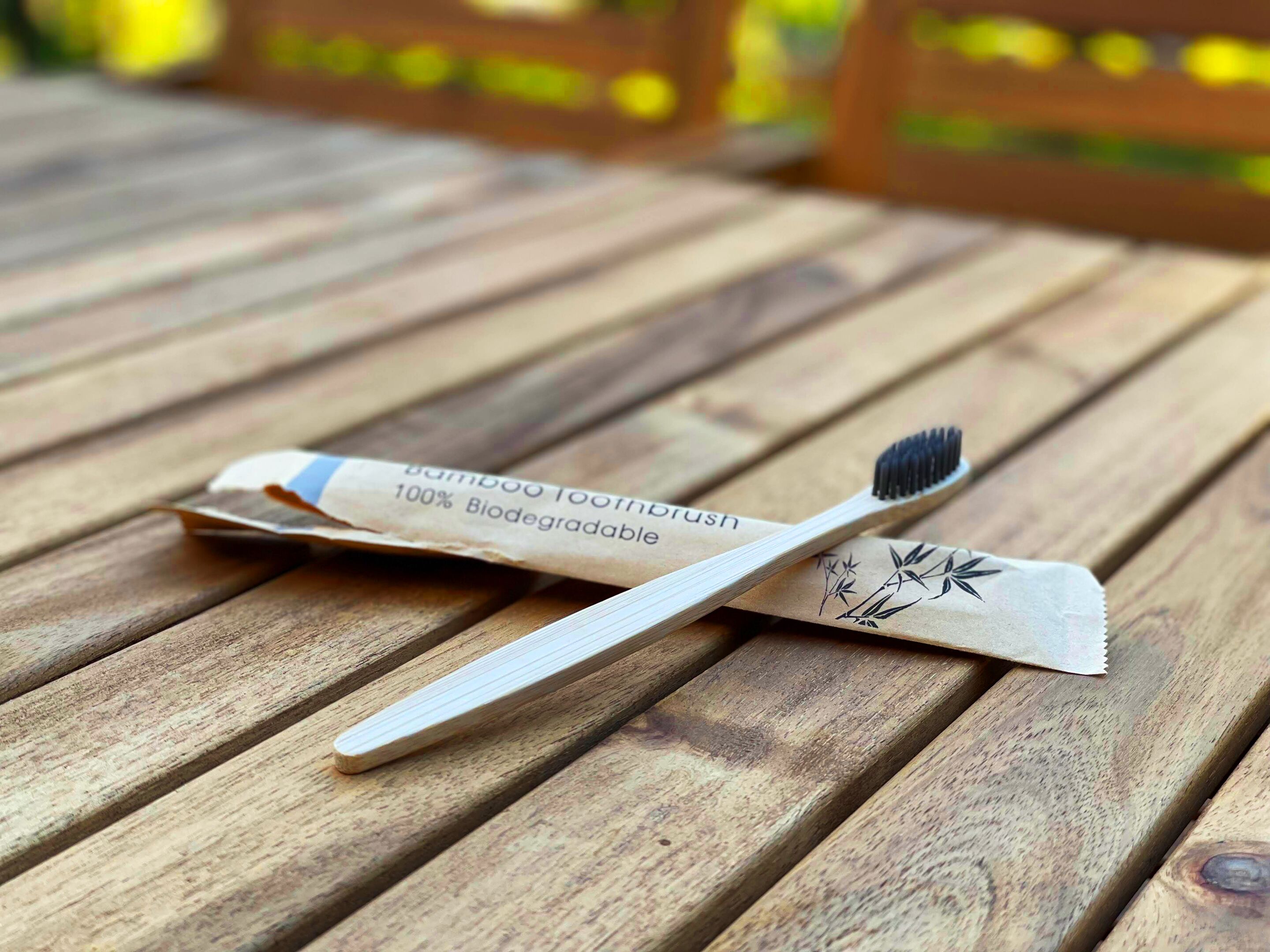 A bamboo toothbrush with a biodegradable handle on a wooden surface.