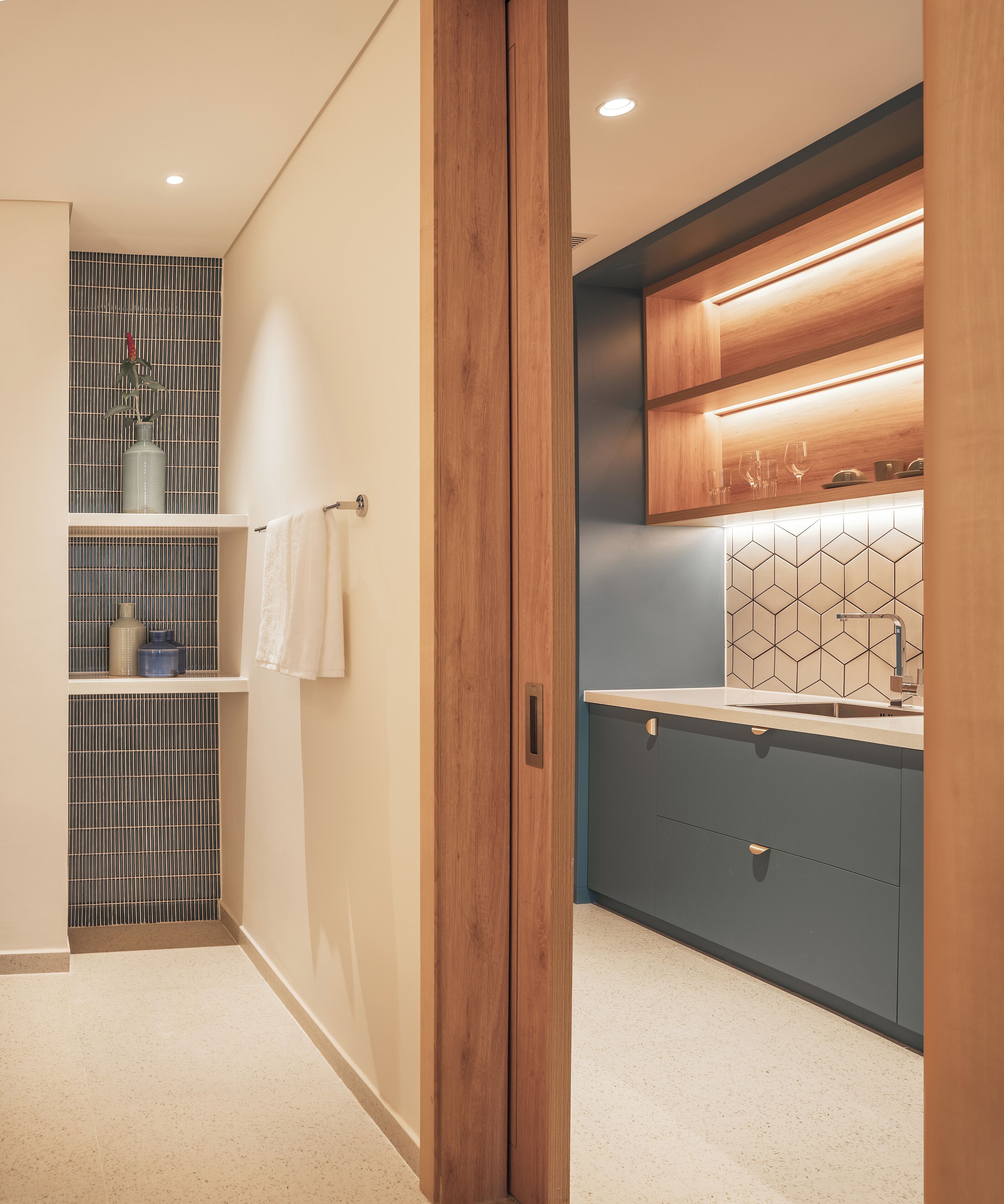 A modern bathroom with a shower, a toilet, and a sink. There is a towel rack and a shelf with toiletries.