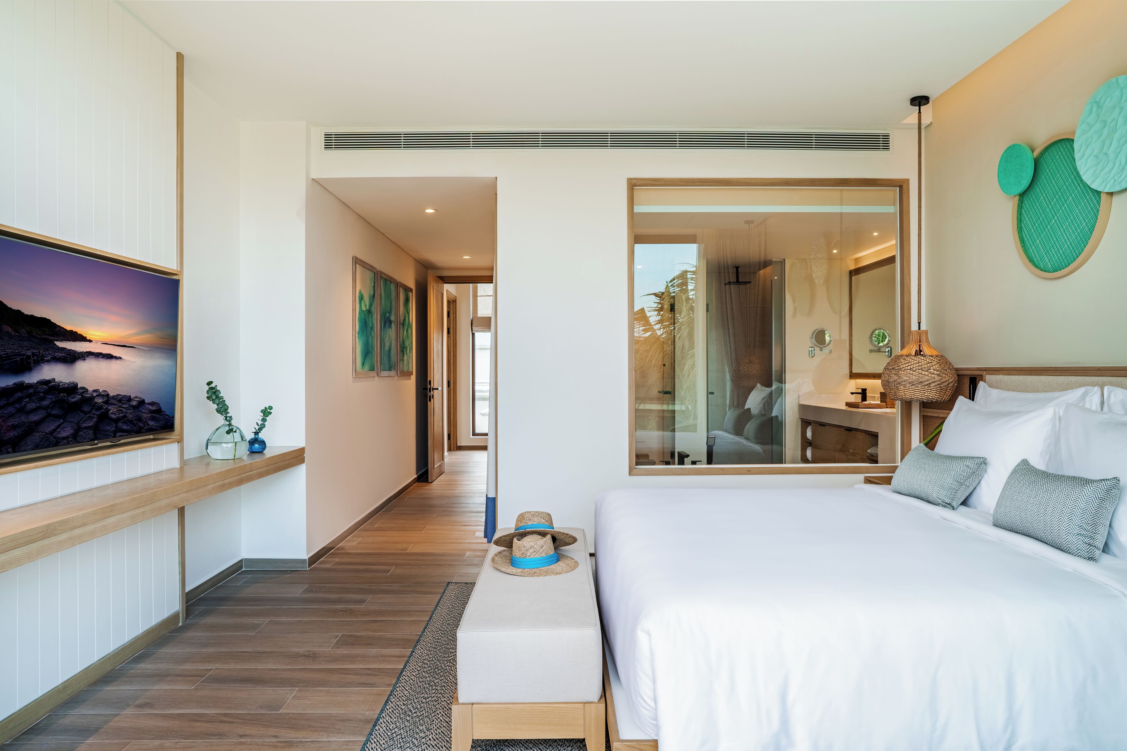 Une chambre d’hôtel moderne avec un grand lit, un banc en bois, un tableau et un grand miroir.