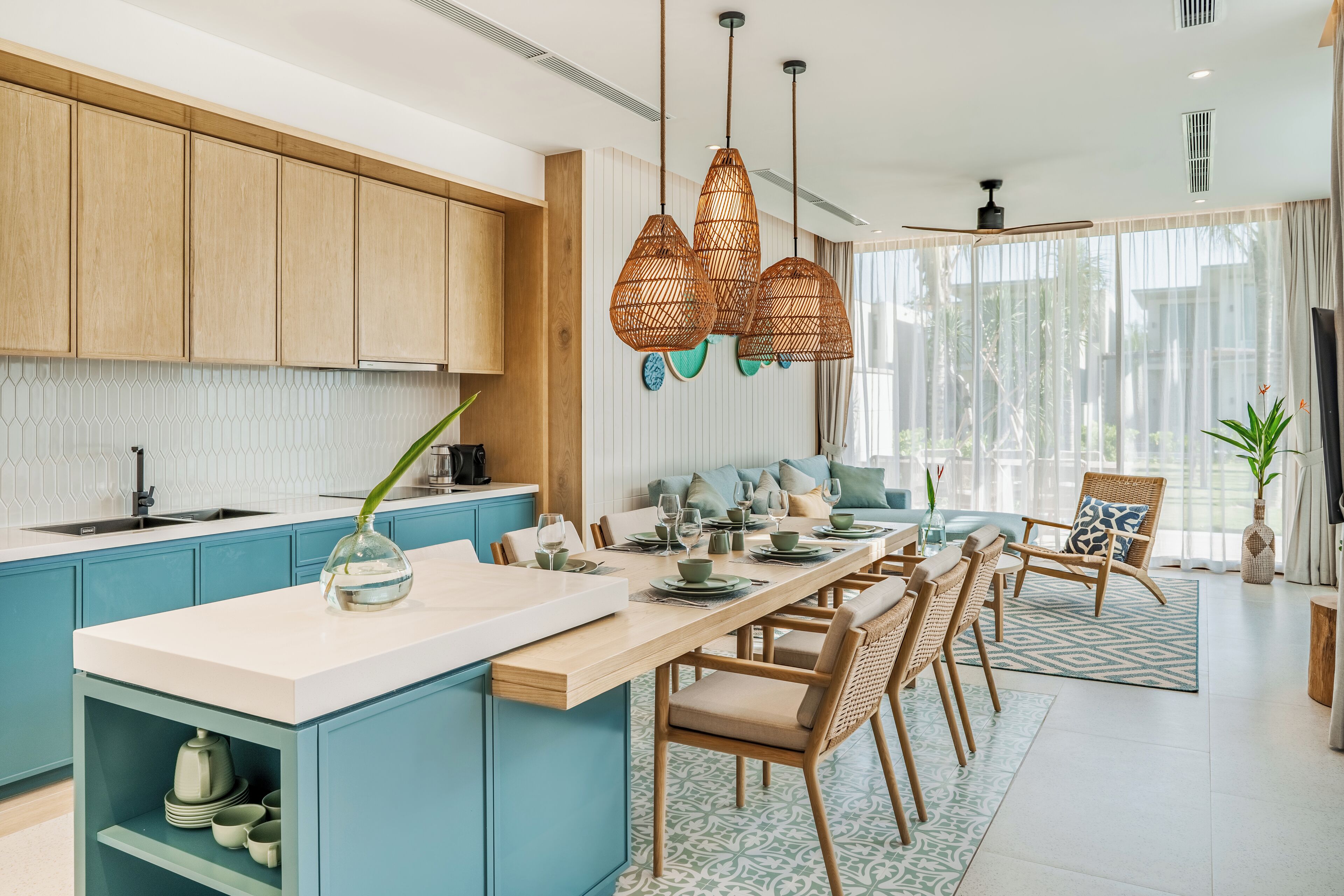 Una cocina moderna con armarios azules, una isla de madera y lámparas colgantes de mimbre.