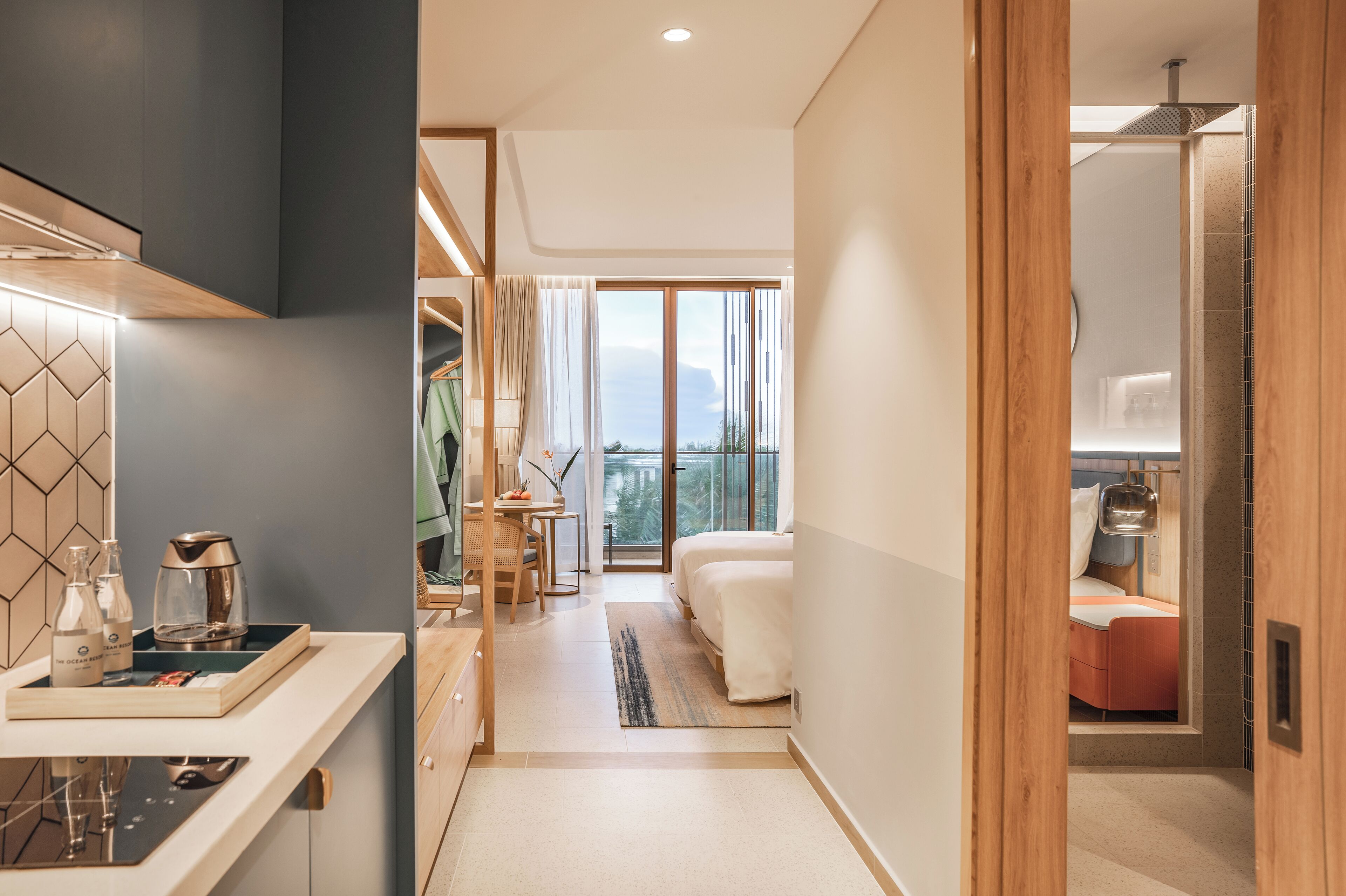A modern hotel room with a kitchen area, a dining space, and a balcony with a view.