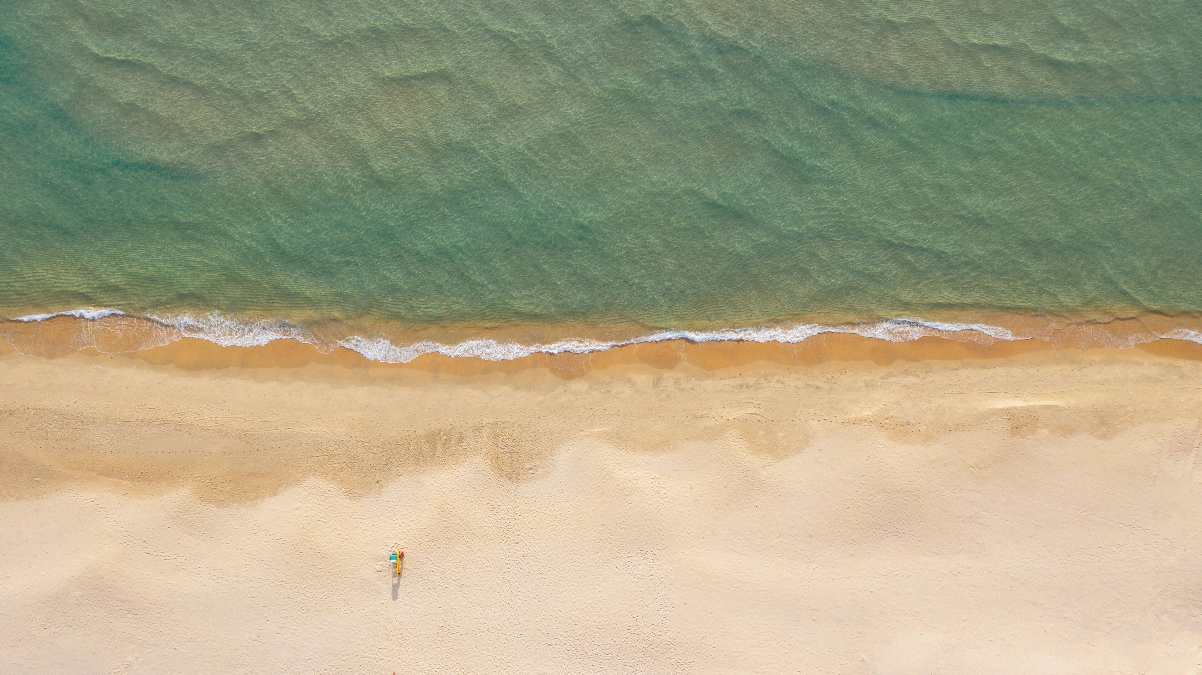 Una playa con agua cristalina y una persona de pie en la arena.