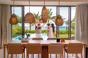 A dining area with a view of the ocean, wicker chairs, and a table with a vase and fruit. - The Ocean Resort by Fusion Quy Nhon (Ngo May)