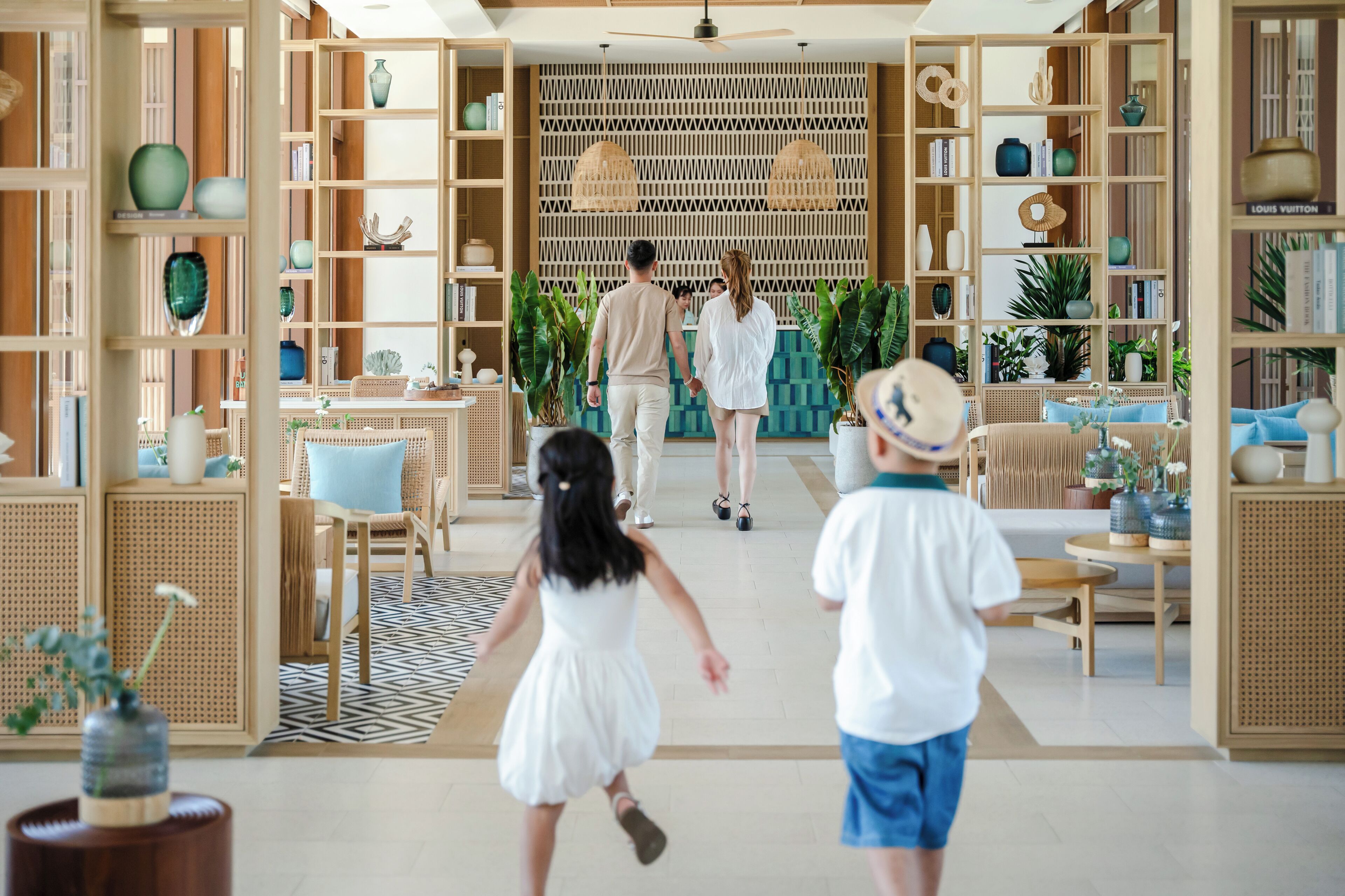 Un hall d’entrée spacieux, doté d’étagères ouvertes où sont exposés divers objets décoratifs, un espace salon central agrémenté d’un tapis à motifs et un ventilateur de plafond moderne.