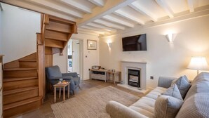 Ein Wohnzimmer mit Kamin, einem an der Wand befestigten Fernseher und einer Treppe zu einem anderen Raum.