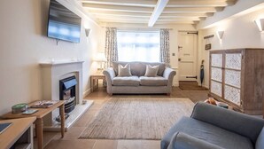 Ein gemütliches Wohnzimmer mit Kamin, einer Couch, einem Fernseher und einem Schrank.