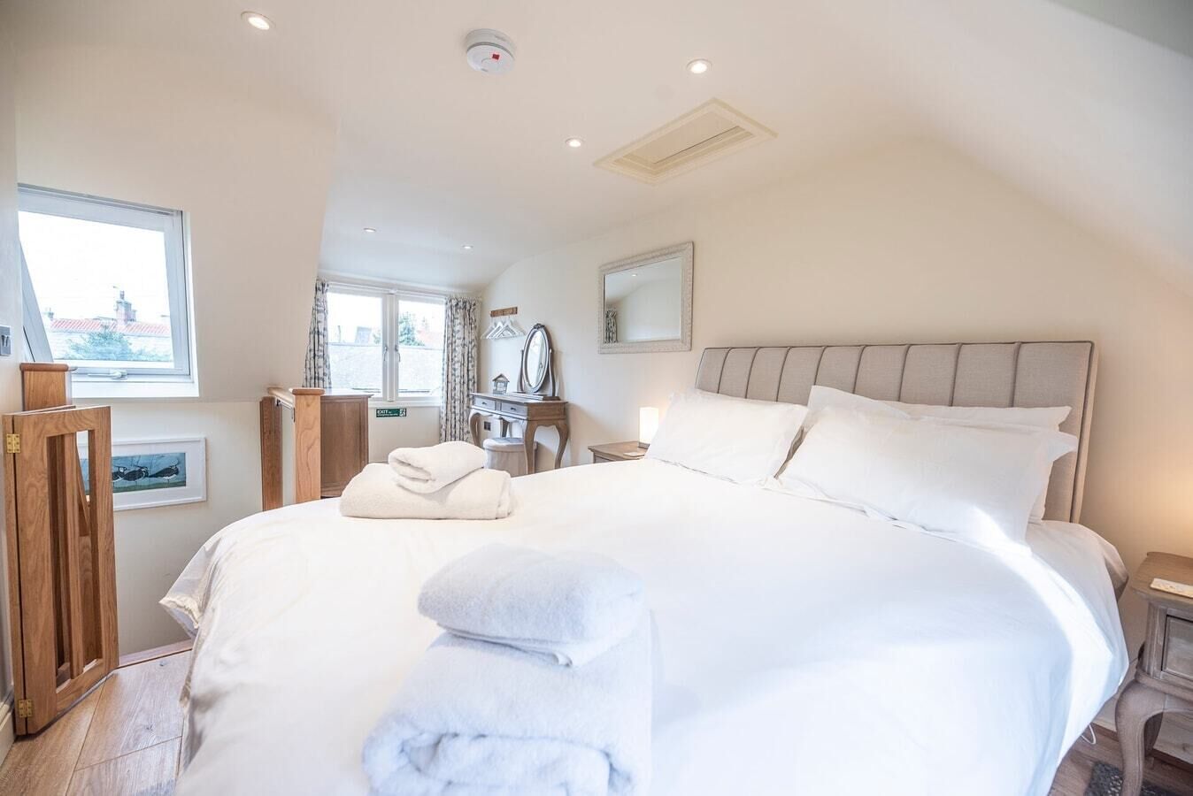 Ruime slaapkamer met een groot bed, nachtkastje, raam en deur.