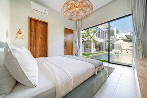 Camera da letto moderna con un letto grande, una porta in legno e vista su piscina e area esterna.