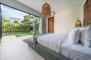 Una camera da letto moderna con un letto grande, vista su un giardino e una lampada a sospensione.