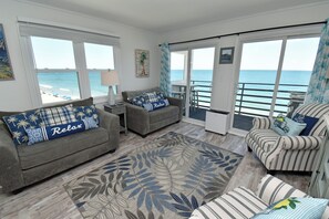 Ein geräumiges Wohnzimmer mit Meerblick, ausgestattet mit einer Couch, einem Sessel und einem Teppich mit Muster.