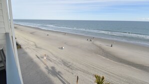 A beach view from a balcony with a clear sky, sandy beach, and ocean. - Carolina Shores II 1404 - Oceanfront Complex in Garden City Beach (Garden City Beach)